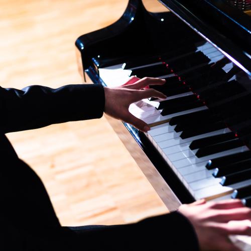 A close-up photo of a piano player's hands on keys.